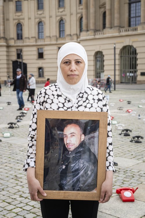 Yasmin Mashaan holding a framed photo of one of her brothers. Credit: Paul Wagner / The Syria Campaign.
